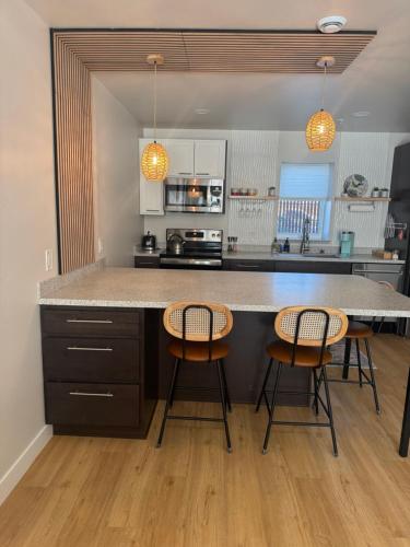 a kitchen with a large counter with three chairs at DWELL in Alaska Apartment h in Fairbanks