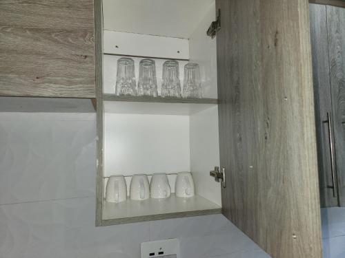a shelf with glasses on it in a room at Sofies's Apartments in Lusaka