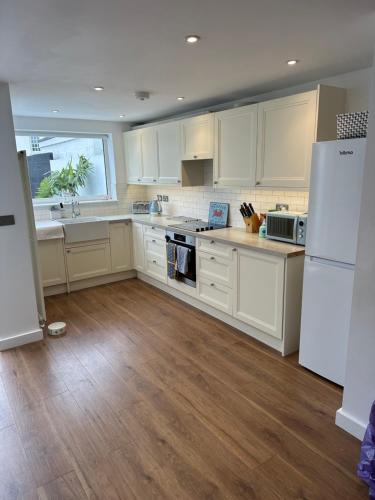 a kitchen with white cabinets and a white refrigerator at Captains Cabin in Walmer
