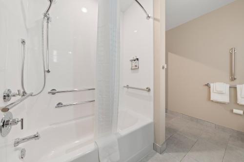 a white bathroom with a shower and a tub at Candlewood Suites Perry-National Fairground Area by IHG in Perry