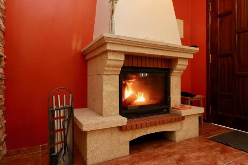 a stone fireplace in a room with a red wall at Villa Rose by AnaLodges in São Vicente