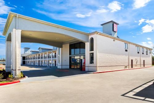 a large white building with a garage at Red Roof Inn Stafford, TX in Stafford