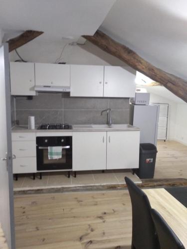 une cuisine avec des armoires blanches et une cuisinière dans l'établissement Chez Amandine, à Molières