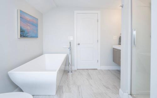 a white bathroom with a large white bath tub at Jennifer's Penthouse 2 Floor Apartment - Amazing City View in Providence