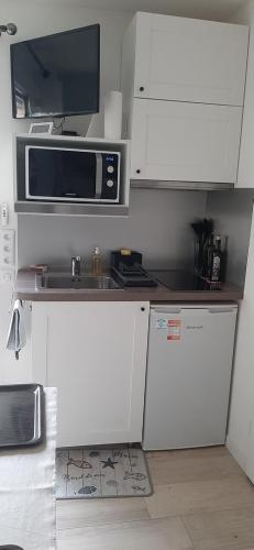 une petite cuisine avec des armoires blanches et un micro-ondes dans l'établissement Chambre d'Hôte Arcachonnaise 41, à Arcachon