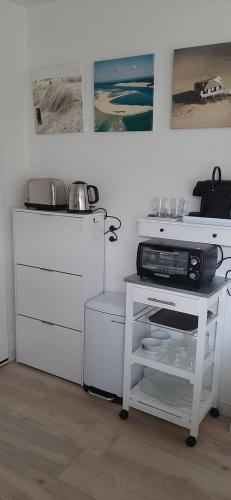 une cuisine avec des placards blancs et un four micro-ondes sur une table dans l'établissement Chambre d'Hôte Arcachonnaise 41, à Arcachon