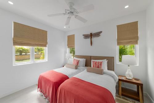two beds in a bedroom with white walls and windows at 17 Westmoreland Hills in Saint James