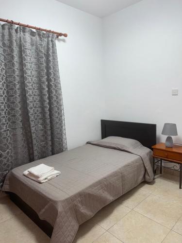 a bedroom with a bed with a curtain and a table at Mythos House in Episkopi Pafou