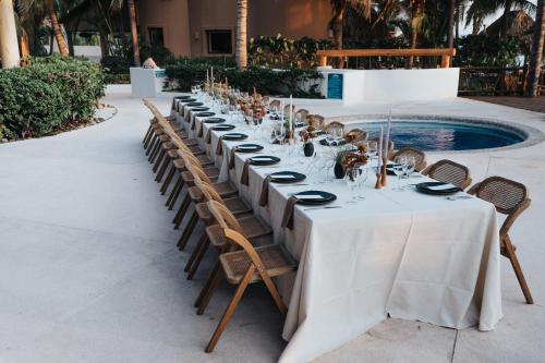 Ein Tisch mit weißer Tischdecke und Stühlen neben einem Pool in der Unterkunft Escondite condominios in Zihuatanejo