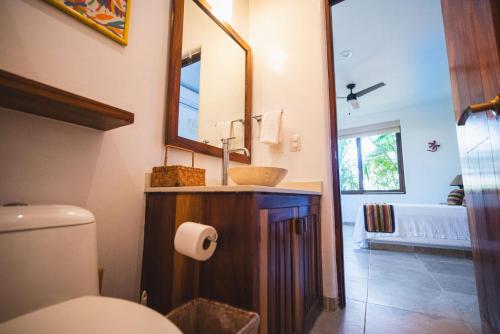 ein Badezimmer mit Waschbecken, Toilette und Spiegel in der Unterkunft Escondite condominios in Zihuatanejo