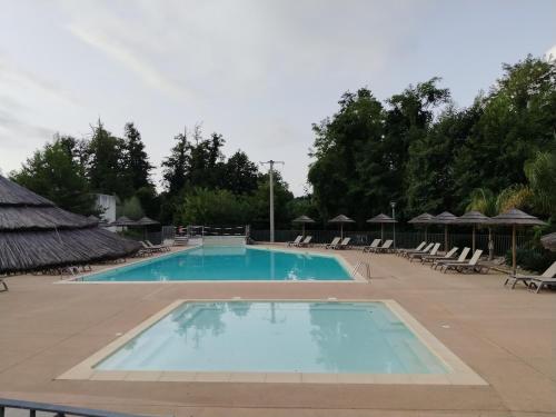 une grande piscine avec chaises longues et parasols dans l'établissement Appartement avec jardin piscine et plage 100 m, à Poggio-Mezzana