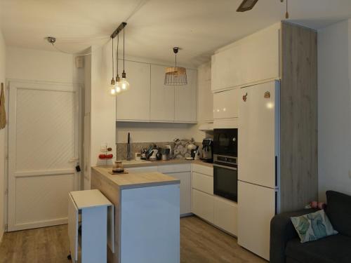 une cuisine avec des armoires blanches et un réfrigérateur blanc dans l'établissement Appartement avec jardin piscine et plage 100 m, à Poggio-Mezzana