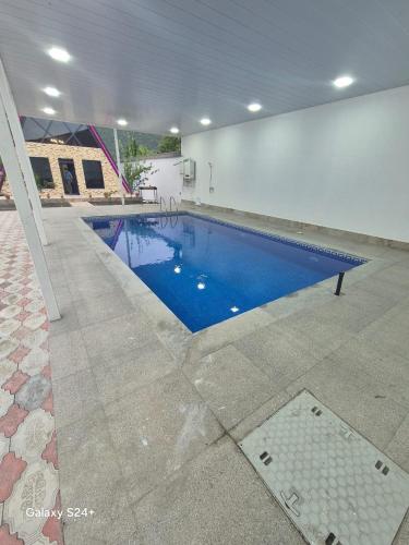 ein großes Schwimmbecken in einem Gebäude mit einem blauen Pool in der Unterkunft BUTAWAY Homes in Qəbələ