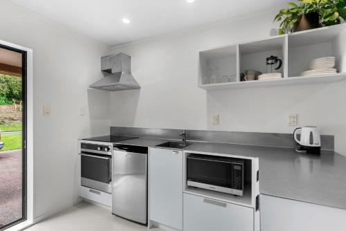 a white kitchen with a sink and a microwave at Bethshan Motel in Algies Bay