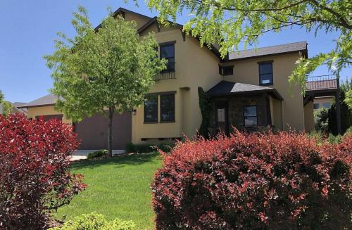 a house with red bushes in front of a yard at The Fireside Retreat - 6 BD, Sauna, Home Theater in Greeley