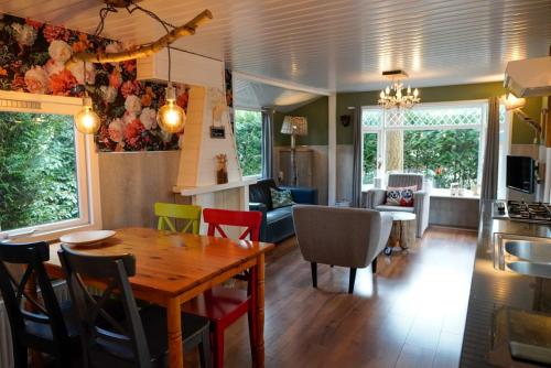 a kitchen and living room with a wooden table and chairs at Chalet Hoenderloo Beuk in Hoenderloo