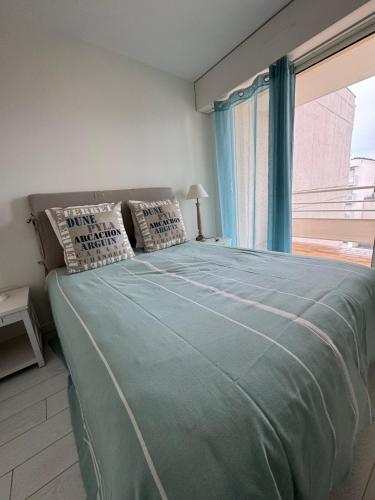 une chambre avec un grand lit avec une fenêtre dans l'établissement Hyper centre Arcachon vu sur le bassin, à Arcachon
