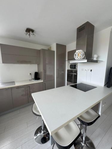 - une cuisine avec une table blanche et des chaises dans l'établissement Hyper centre Arcachon vu sur le bassin, à Arcachon
