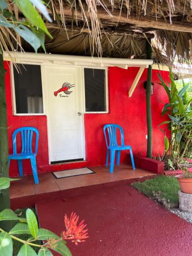 two blue chairs sitting in front of a red house at Arena Oceanview Hotel & La Terraza Restaurant in Las Galeras
