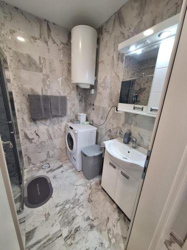 a marble bathroom with a sink and a toilet at Apartman MILOVANOVIĆ in Vrnjačka Banja