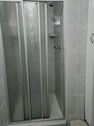 a shower with a glass door in a bathroom at MayBach Hills Palace Guesthouse in Saldanha