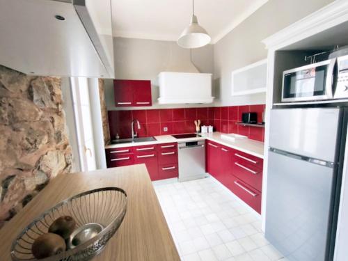 - une cuisine avec des placards rouges et un bol de fruits sur une table dans l'établissement Villa de charme, aux Arcs-sur-Argens