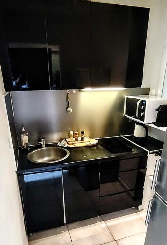 une cuisine avec un évier et un micro-ondes dans l'établissement Studio cosy Balcon Aperçu mer, à Antibes