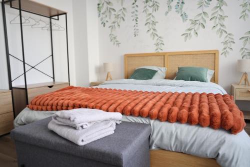 - une chambre avec un grand lit et une grande couverture orange dans l'établissement Le Verdoyant , maisonnette cosy avec terrasse, à Hagondange