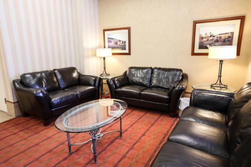 a living room with leather furniture and a glass table at Hôtels Gouverneur Trois-Rivières in Trois-Rivières