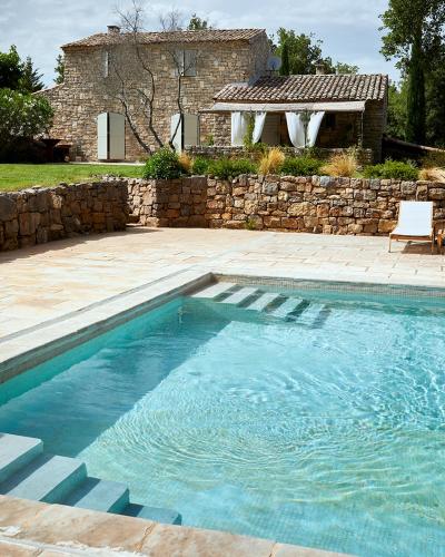 une piscine devant une maison avec un mur en pierre dans l'établissement Havre de paix et de charme avec piscine, à Saint-Maximin-la-Sainte-Baume