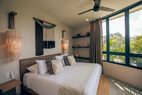 a bedroom with a bed and a large window at Boho Jungle Villa - Pvt Pool -100mbs- Concierge 7A in Tulum