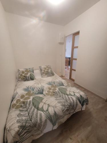 une chambre blanche avec un lit avec un couvre-lit fleuri dans l'établissement Résidence Pifourcha La Roche Entre Sisteron & Serre-Ponçon, à Le Caire