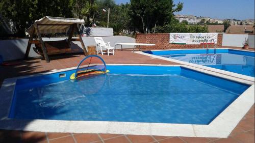a large blue swimming pool with a swing at B&B Troisi in Racalmuto
