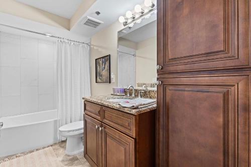 baño con armario de madera con lavabo y aseo en DiMucci Tower 201, en Daytona Beach Shores