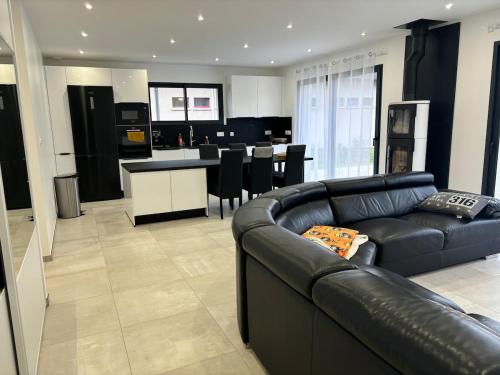 Il comprend un salon avec un canapé en cuir noir et une cuisine. dans l'établissement Maison neuve à la montagne, à Le Châtelard