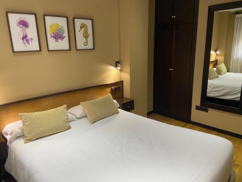 a bedroom with a large white bed and a mirror at Hotel Apartamento Marouco in A Guarda
