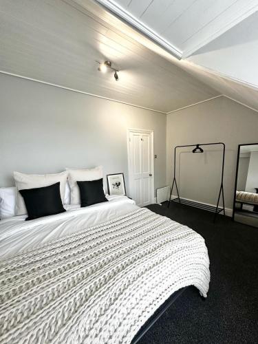 a bedroom with a large white bed with black pillows at Luxury 5 bed Salford home free parking in Manchester