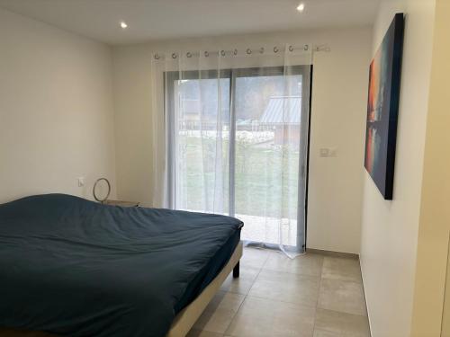 una camera da letto con un letto e una grande finestra di Maison neuve à la montagne a Le Châtelard