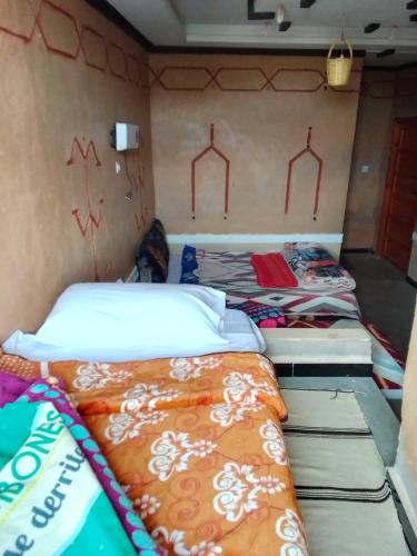 a group of beds in a room with graffiti on the wall at Ait Sedrate Tourism Cooperative Hotel in Boumalne