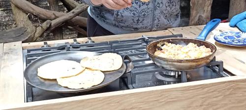 a person cooking food in a pan on a stove at Mindfulness Glamping, Retiro de Yoga, Todo Incluido in Mexico City
