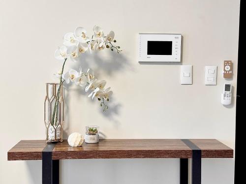 a table with a vase of flowers on a wall at City Lights Apartment in BGC in Manila