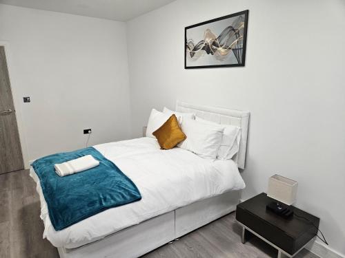 a bedroom with a white bed with a blue blanket at Kingdom apartments in Wolverhampton