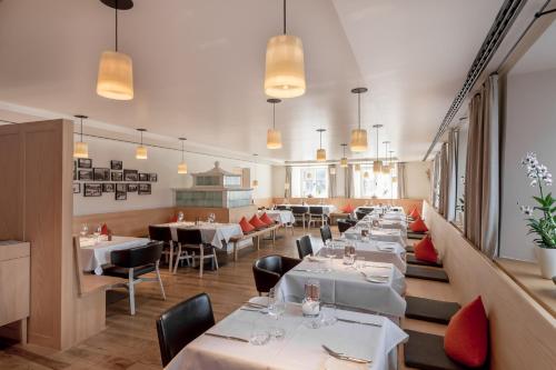 a restaurant with white tables and chairs and lights at Alpenhotel Krone in Pfronten