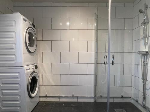 Baño de azulejos blancos con lavadora y secadora en Märsta Apartment Hotel, en Märsta
