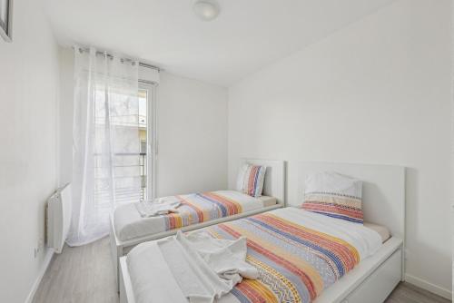 Cette chambre blanche dispose de deux lits et d'une fenêtre. dans l'établissement Paris Disney an unforgettable stay comfortable, à Montévrain