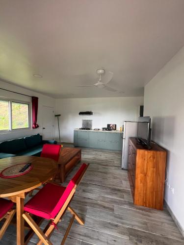 a living room with a table and a kitchen at Painapoo - Mirimiri Lodge in Tevaitoa