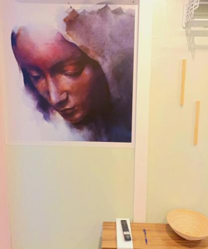 a painting of a woman on a wall next to a table at Home4U Κερατέα apt5, just 17Km from airport in Keratea