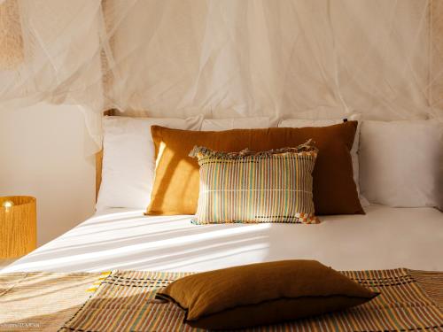 a white bed with two pillows and a pillow on it at Chez Paulette à distance à pied de la plage et piscine chauffée in Friar's Bay