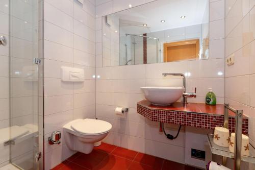 Un baño con lavabo, inodoro y espejo. en Yachthafenresidenz-Wohnung-9303-887, en Kühlungsborn