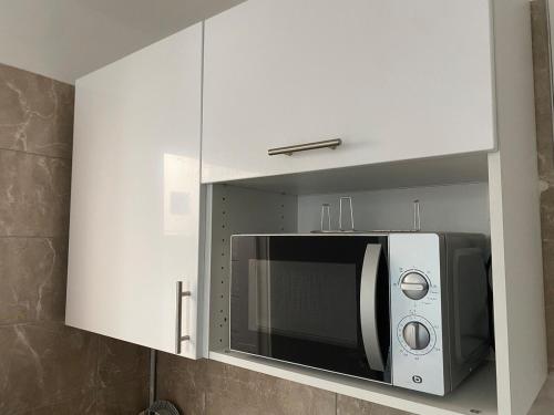 a microwave in a white cabinet in a kitchen at Studio au cœur de Montmartre in Paris